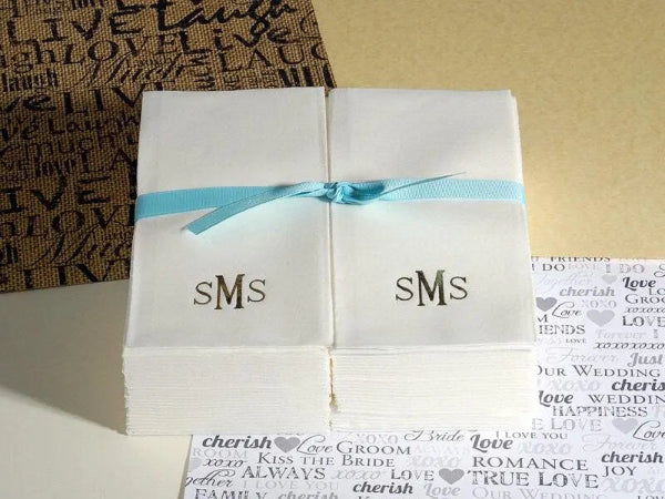 Folded white paper with 'SMS' monogram tied with a blue ribbon on a textured surface.