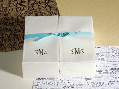 Folded white paper with 'SMS' monogram tied with a blue ribbon on a textured surface.